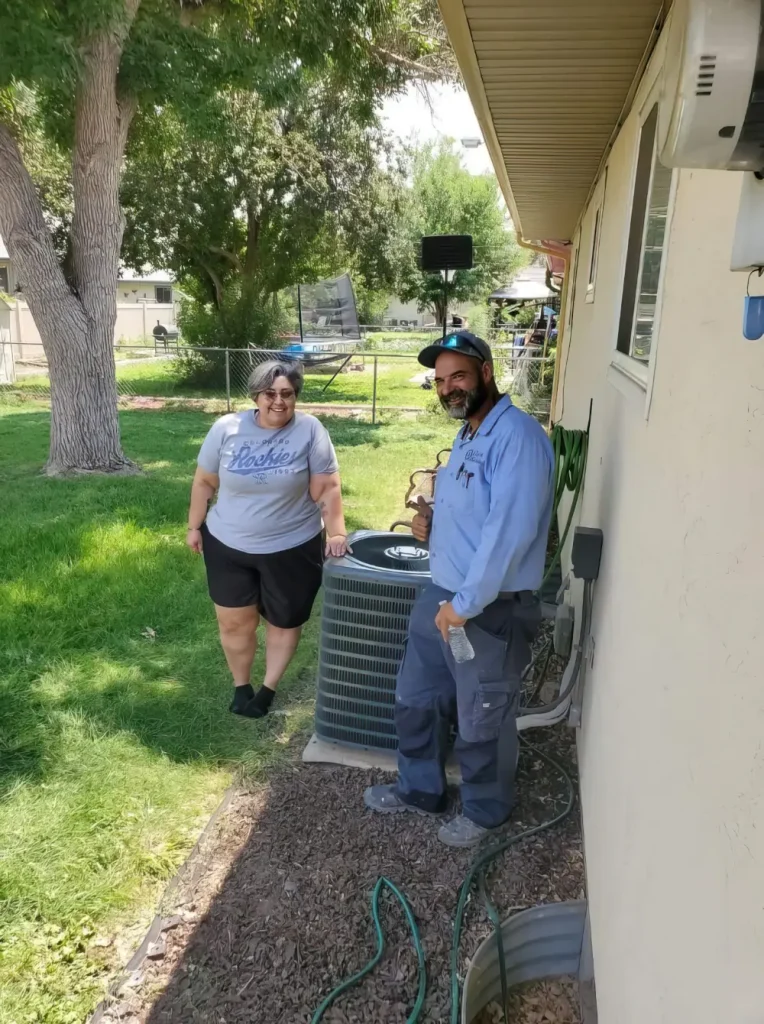 AC Installation In Pueblo, Co - Picture of a Clarks technician with a happy customer. Both are standing next to a newly installed AC unit.