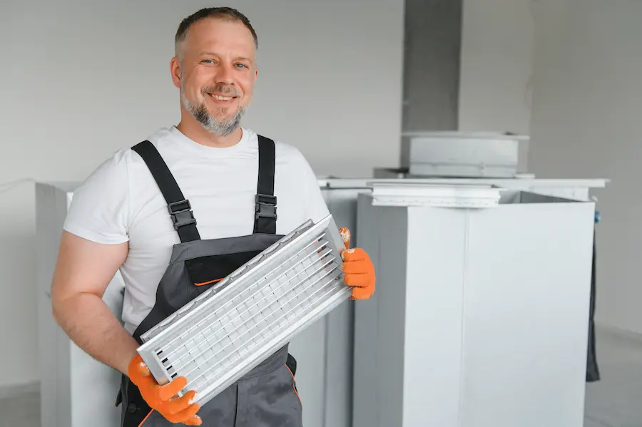 HVAC Services In Salt Creek, CO | Clarks Mechanical - A male worker holds an air filter for air conditioning in an office space. Installation of an air conditioner